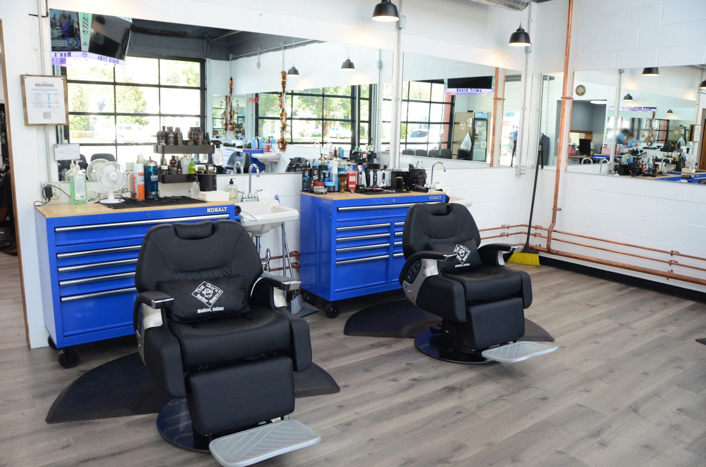 Inside That Guys Barber Shop: two black barber chairs in front of blue tool chests and big mirrors